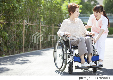 女性介護士と車いすに乗った中高年女性 13709064