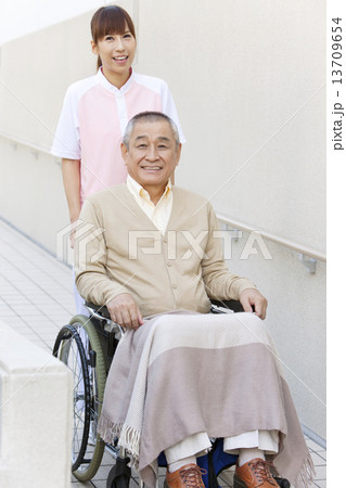 女性介護士と車いすに乗った中高年男性 13709654