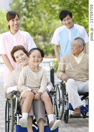 介護士と孫と車いすに乗った中高年男女 13709709