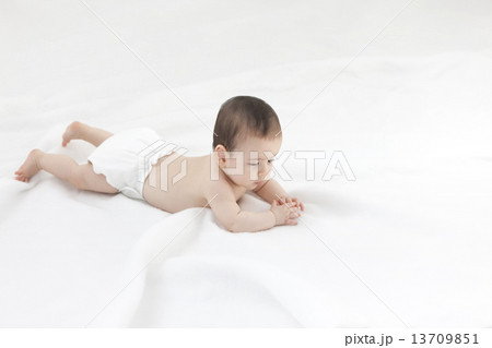 シーツに寝そべる赤ちゃん 13709851