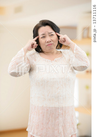 室内に立っている、腰痛、肩こりに悩んでいるカジュアルウェアー姿の中年女性 13711116