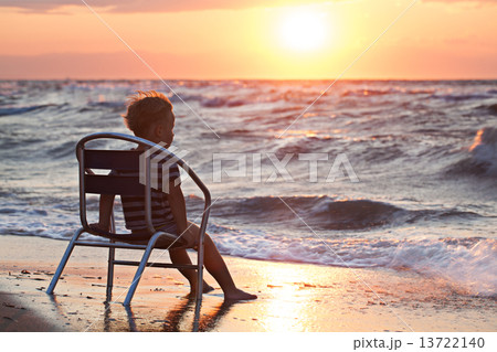 Little child looking at sunset sitting by the sea Little child looking at sunset sitting by the sea 13722140