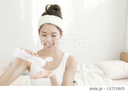 化粧水を手に取る若い女性の写真素材