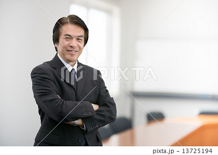 会社の会議室に立っているスーツ姿の中年男性 会社の会議室に立っているスーツ姿の中年男性 13725194