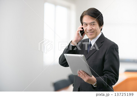 会社の会議室に立っているスーツ姿の中年男性 13725199