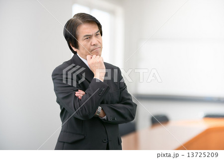 会社の会議室に立っているスーツ姿の中年男性 会社の会議室に立っているスーツ姿の中年男性 13725209