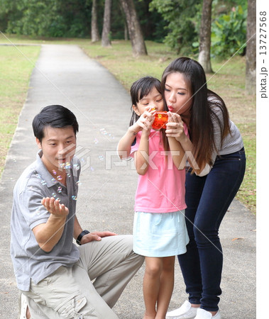 Parents and daughter in the park playing bubble Parents and daughter in the park playing bubble 13727568