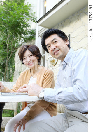 庭でパソコンをするシニア夫婦 13730495