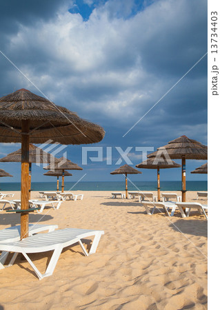 Different parasols and sun loungers on the empty beach on Tavira 13734403