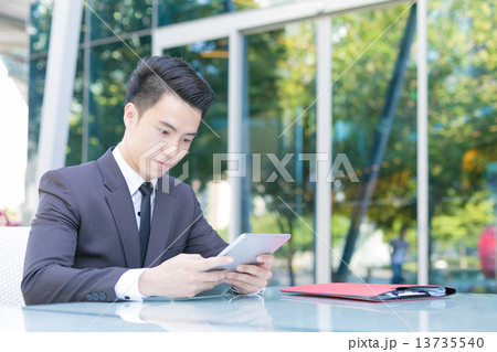 A businessman is reading message from his tablet computer 13735540