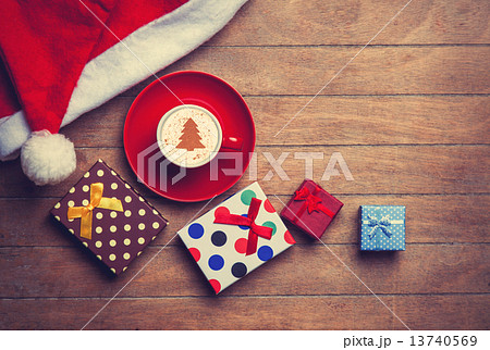 Cappuccino with christmas hat and gift on wooden table. Cappuccino with christmas hat and gift on wooden table. 13740569