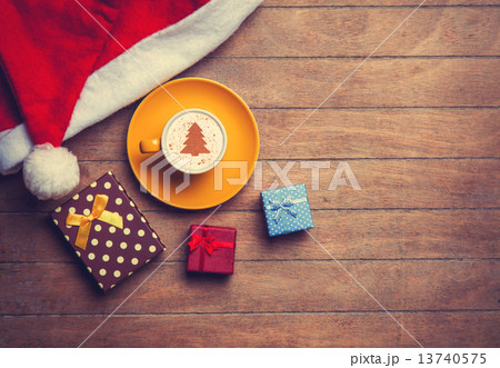 Cappuccino with christmas hat and gift on wooden table. 13740575