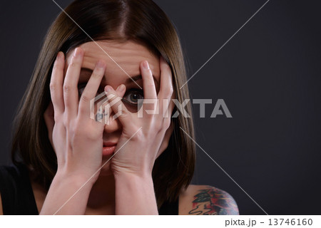 Teenage girl frightened looking through fingers 13746160