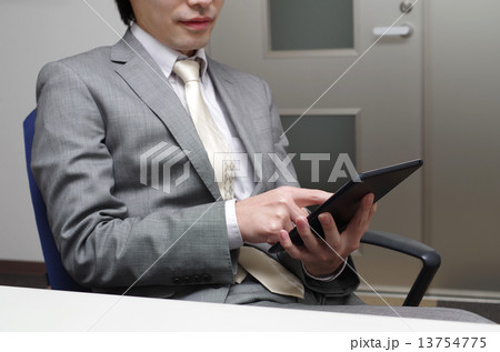 リラックスしてタブレットをいじるビジネスマン 13754775