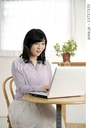 部屋でパソコンを使う若い女性 部屋でパソコンを使う若い女性 13757320