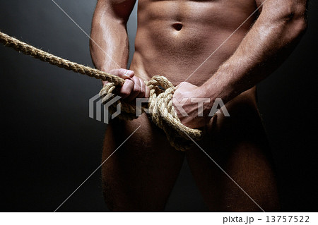 Studio shot of naked strong man tied with rope 13757522