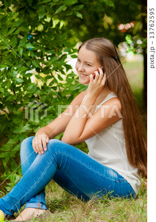 Teenage girl with a mobile phone near a tree 13762595