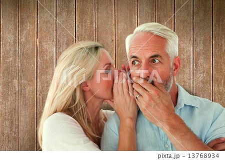 Composite image of woman whispering a secret to husband Composite image of woman whispering a secret to husband 13768934