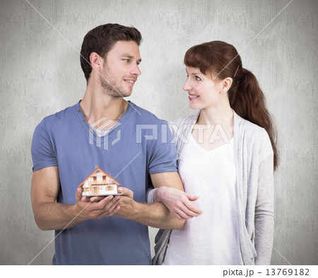 Composite image of couple holding a model house Composite image of couple holding a model house 13769182