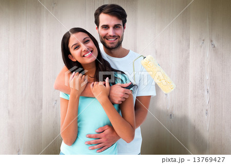 Composite image of happy young couple painting together 13769427