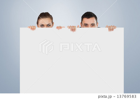 Composite image of business partners hiding behind a sign Composite image of business partners hiding behind a sign 13769583