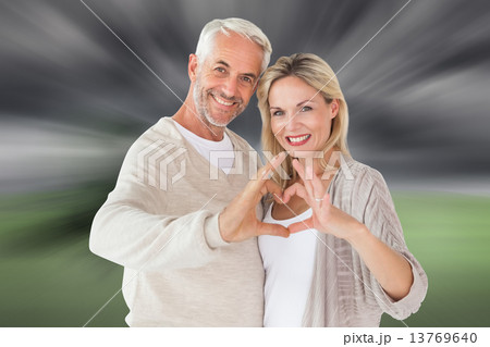 Composite image of happy couple forming heart shape with hands 13769640