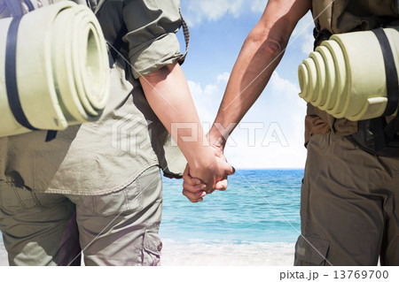 Composite image of hitch hiking couple standing holding hands on 13769700