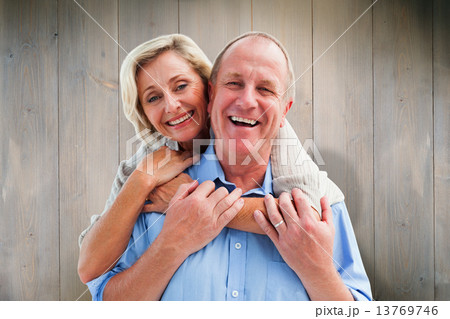 Composite image of happy mature couple embracing smiling at came 13769746