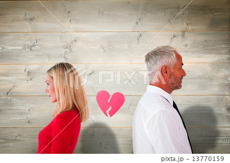 Composite image of couple not talking with broken heart between Composite image of couple not talking with broken heart between 13770159