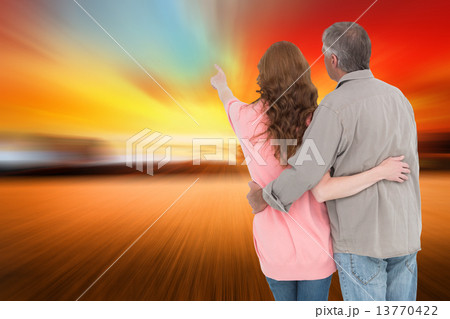 Composite image of casual couple standing arms around 13770422