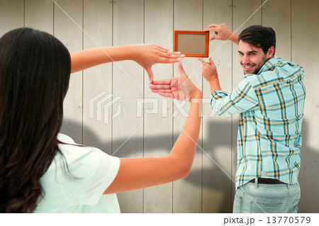 Composite image of happy young couple putting up picture frame Composite image of happy young couple putting up picture frame 13770579
