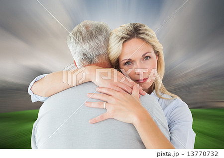 Composite image of unhappy blonde hugging her husband 13770732