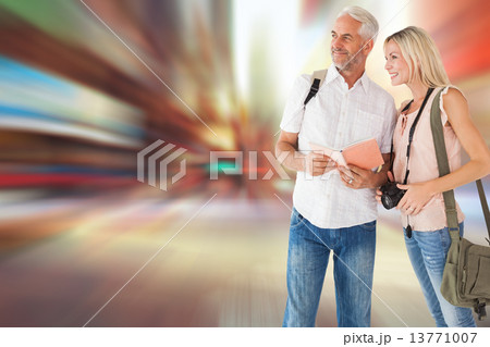 Composite image of happy tourist couple using the guidebook 13771007