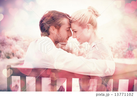 Cute couple sitting on bench together smiling at each other 13771102