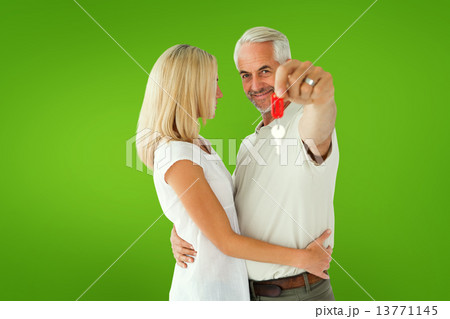 Composite image of happy couple showing their new house key Composite image of happy couple showing their new house key 13771145
