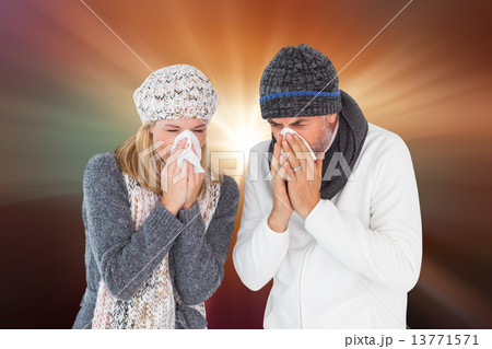 Composite image of sick couple in winter fashion sneezing Composite image of sick couple in winter fashion sneezing 13771571