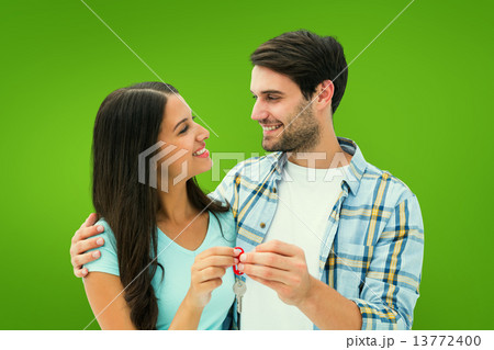 Composite image of happy young couple holding new house key Composite image of happy young couple holding new house key 13772400