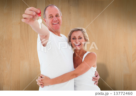 Composite image of mature couple smiling at camera with new hous Composite image of mature couple smiling at camera with new hous 13772460