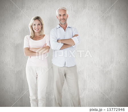 Composite image of smiling couple standing with arms crossed 13772946