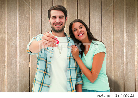 Composite image of happy young couple showing new house key Composite image of happy young couple showing new house key 13773023