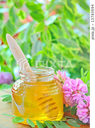 glass jar full of honey and stick with acacia pink and white flo glass jar full of honey and stick with acacia pink and white flo 13783694