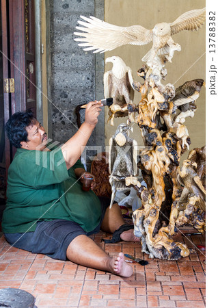 A man is saturating a wooden statue with a stain A man is saturating a wooden statue with a stain 13788382