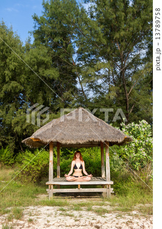 Woman doing yoga meditation in tropical gazebo Woman doing yoga meditation in tropical gazebo 13789758