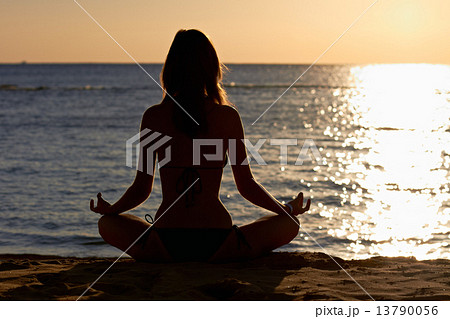 Woman in yoga lotus meditation front to seaside 13790056