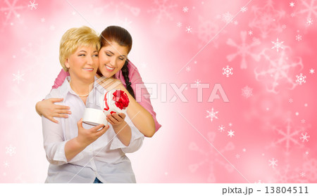 Young girl giving gift to her mother on winter background 13804511