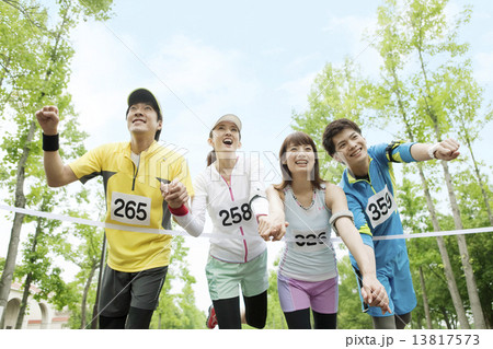 ゴールテープを切る男女4人の写真素材