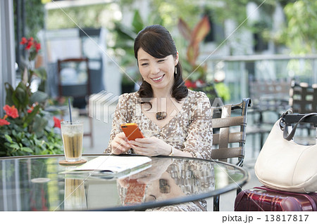 カフェで携帯電話を見る中高年女性 13817817