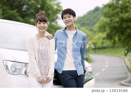 車の前に立つカップル 13819166