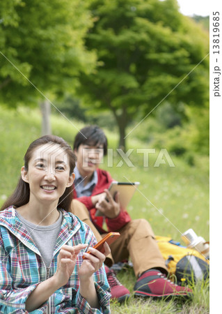携帯電話を持つ女性とタブレットPCを持つ男性 13819685