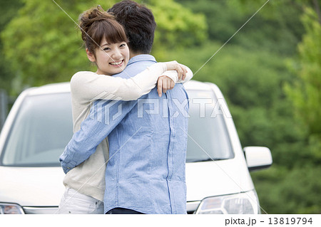 車の前で抱き合うカップルの写真素材